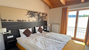 Une chambre d’hôtel avec un plafond en bois, un grand lit avec une literie blanche, une table de chevet, une lampe et une vue sur l’extérieur par une fenêtre.