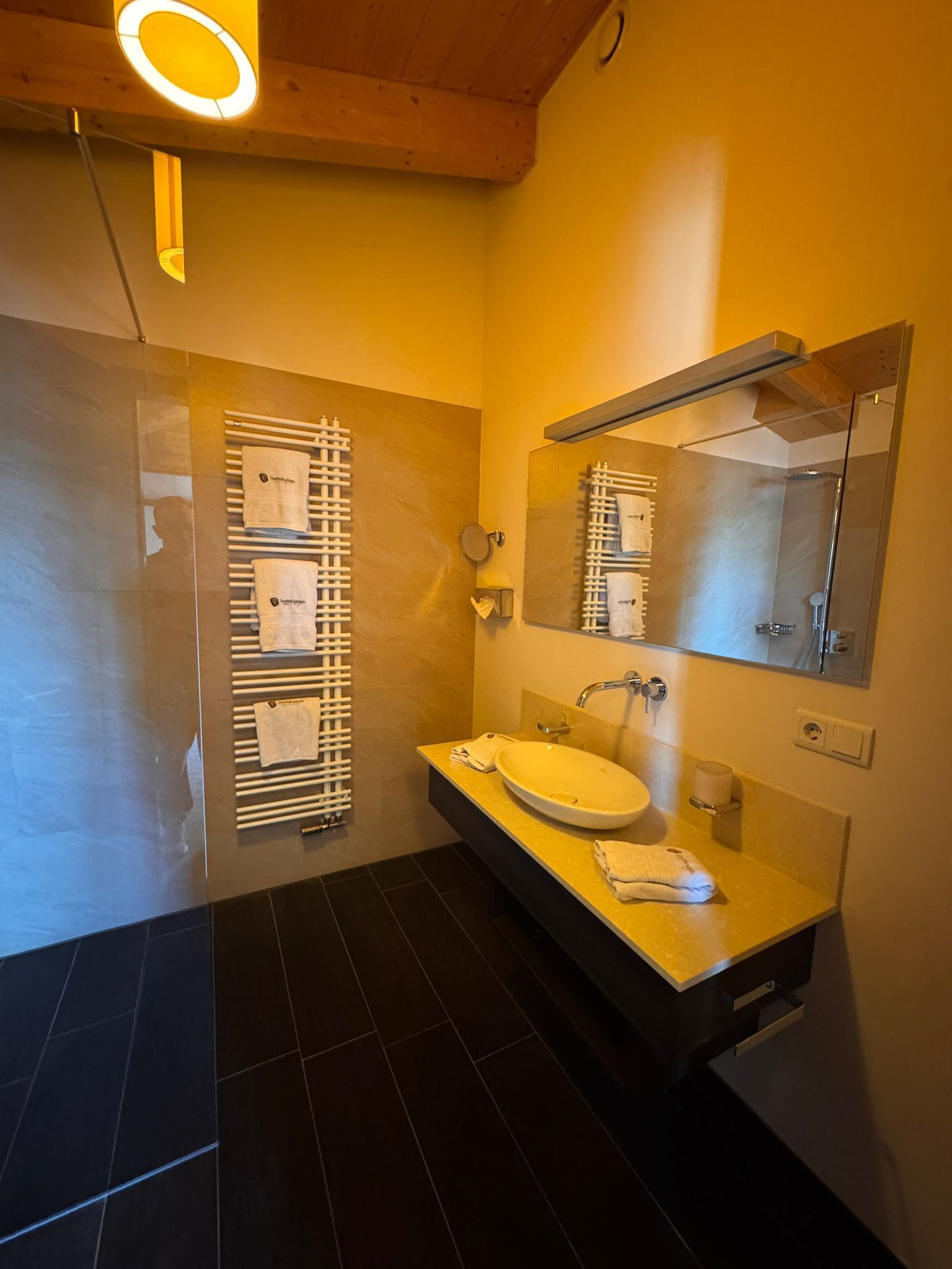 Ein modernes Badezimmer mit einem großen Spiegel, einem runden Waschbecken und einem Handtuchhalter.