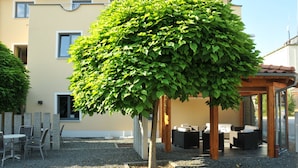 Un bâtiment doté d’un patio avec espace extérieur aménagé pour s’asseoir et d’un jardin bien entretenu.