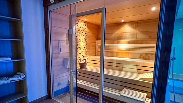 Un sauna avec des bancs en bois et une porte en verre.