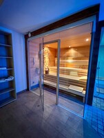 Una sala de sauna con bancos de madera y una puerta de cristal.