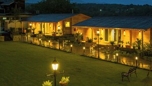 Een goed verlicht hotel met een binnentuin, terras en een berg op de achtergrond.