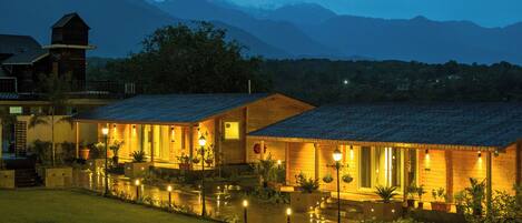 A well-lit hotel with a courtyard, outdoor seating, and a mountain backdrop.