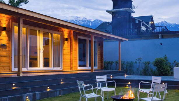 Een modern huis met terras, zitplaatsen buiten en een vuurkorf.
