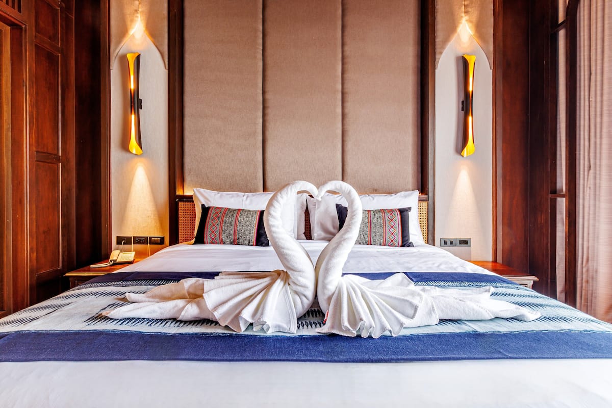 Une chambre d’hôtel avec un lit, des oreillers et une lampe fixée au mur.