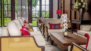 A spacious living room with wicker furniture, a wooden coffee table, and a vase of flowers. - S48 River Ping Hotel (Chiang Mai)