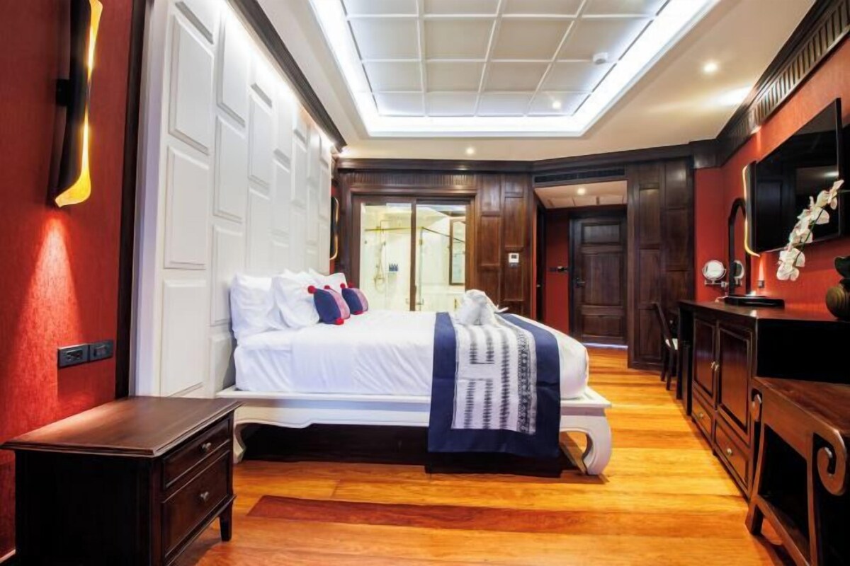 A bedroom with a large bed, wooden floor, and a ceiling light fixture.