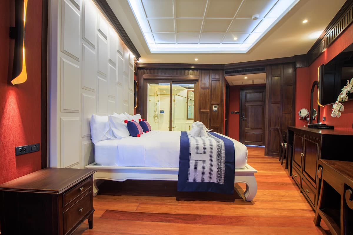 Une chambre d’hôtel avec un grand lit, un bureau, un miroir et un luminaire au plafond.