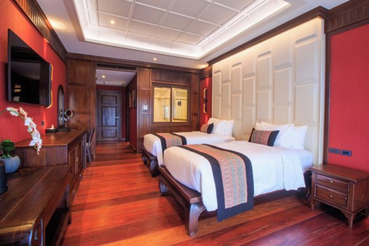 Une chambre d’hôtel avec un plancher en bois, un grand lit avec deux oreillers, une table de chevet et un téléviseur fixé au mur.
