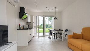 A modern kitchen with white cabinets, a dining area with a table and chairs, and a sofa in a bright living space. - Armonia Suites - Aria -Relax & Nature Just Minutes from Verona (Verona)