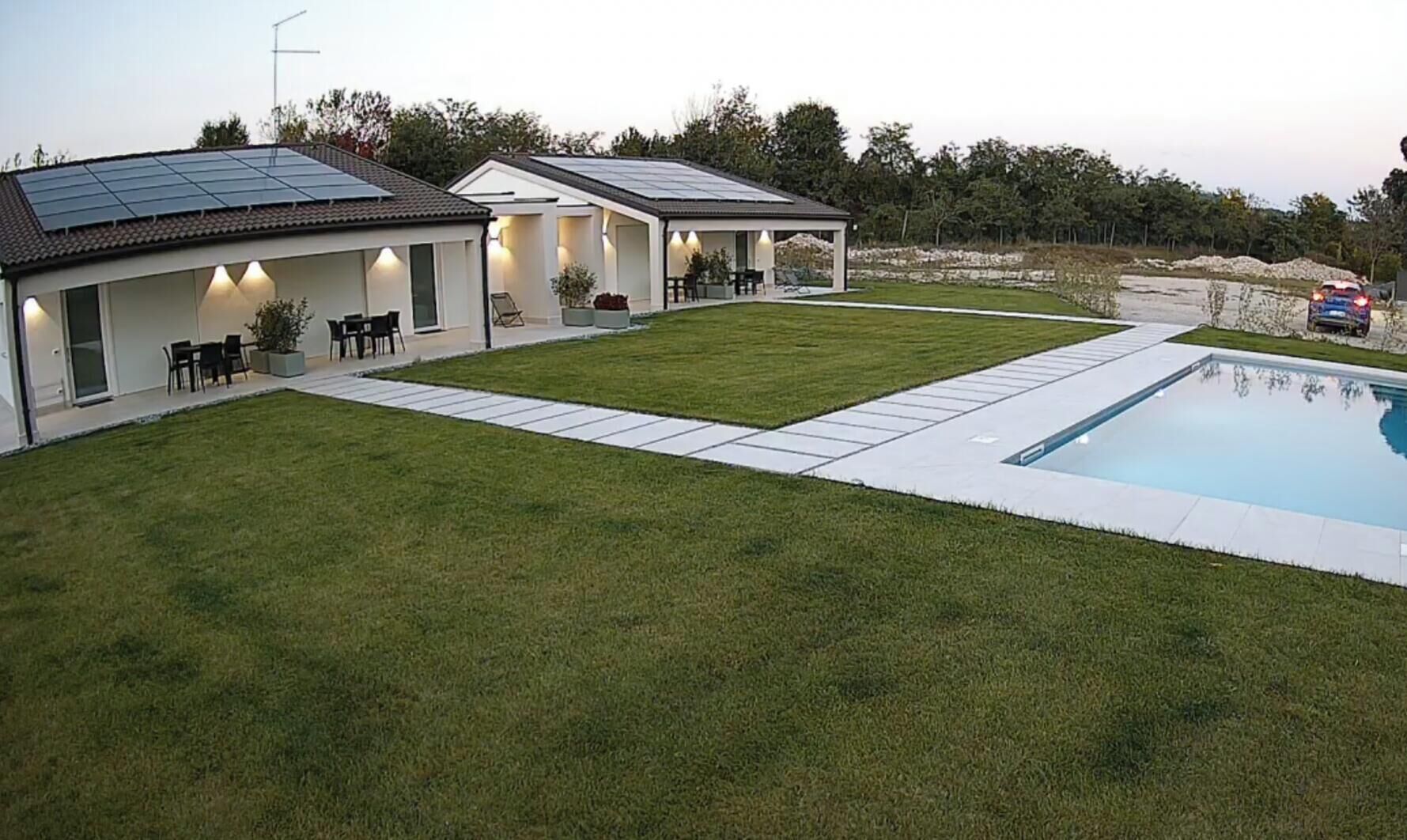 Een modern huis met zonnepanelen, een zwembad en een verzorgd gazon.