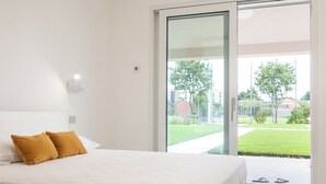A modern bedroom with a large bed, white walls, a glass door leading to a balcony, and a ceiling light fixture. - Armonia Suites - Aria -Relax & Nature Just Minutes from Verona (Verona)