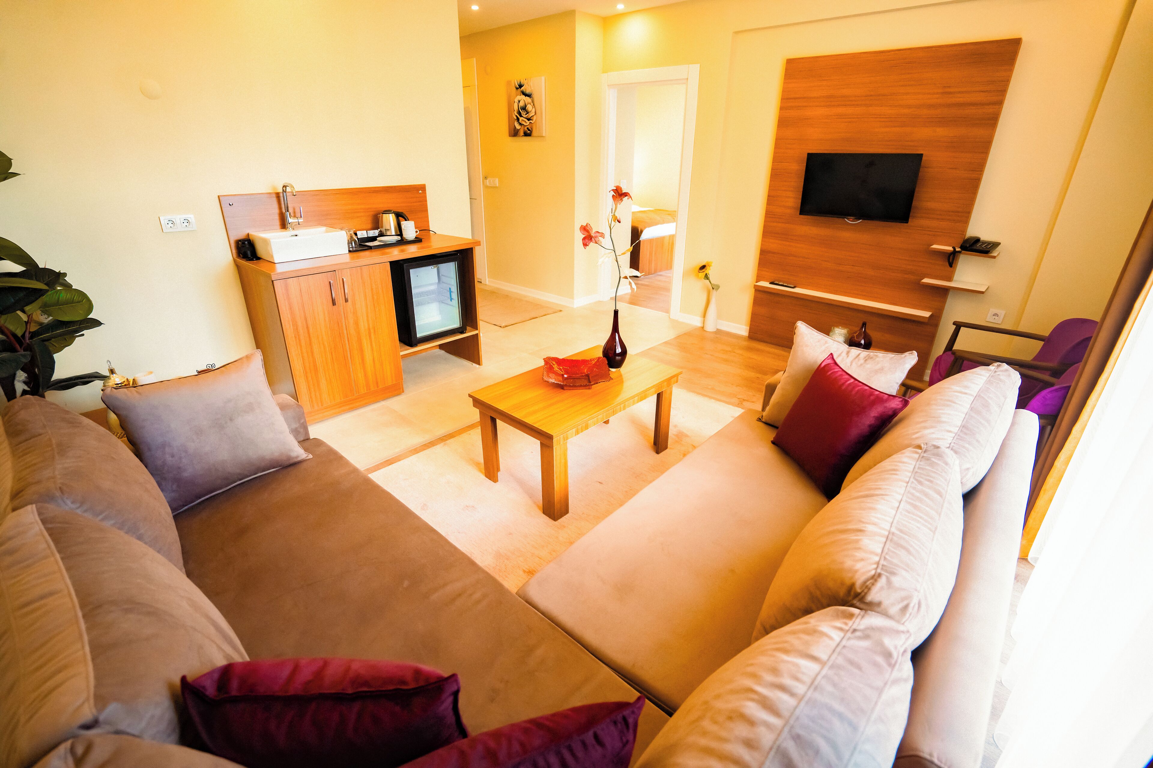 A living room with a sofa, a coffee table, and a TV mounted on the wall.