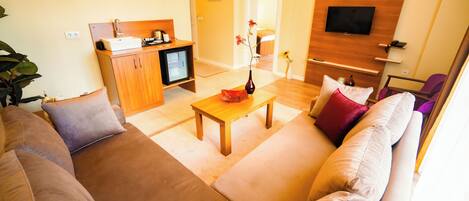 A living room with a sofa, a coffee table, and a TV mounted on the wall.