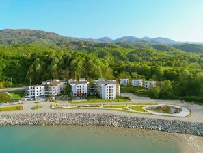 Un resort con varias edificaciones blancas, un patio central y un exuberante paisaje verde que lo rodea.