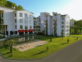 Un hotel moderno de varios pisos con terraza al aire libre y un césped bien cuidado.