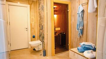 A bathroom with a toilet, a sink, and a shower area.