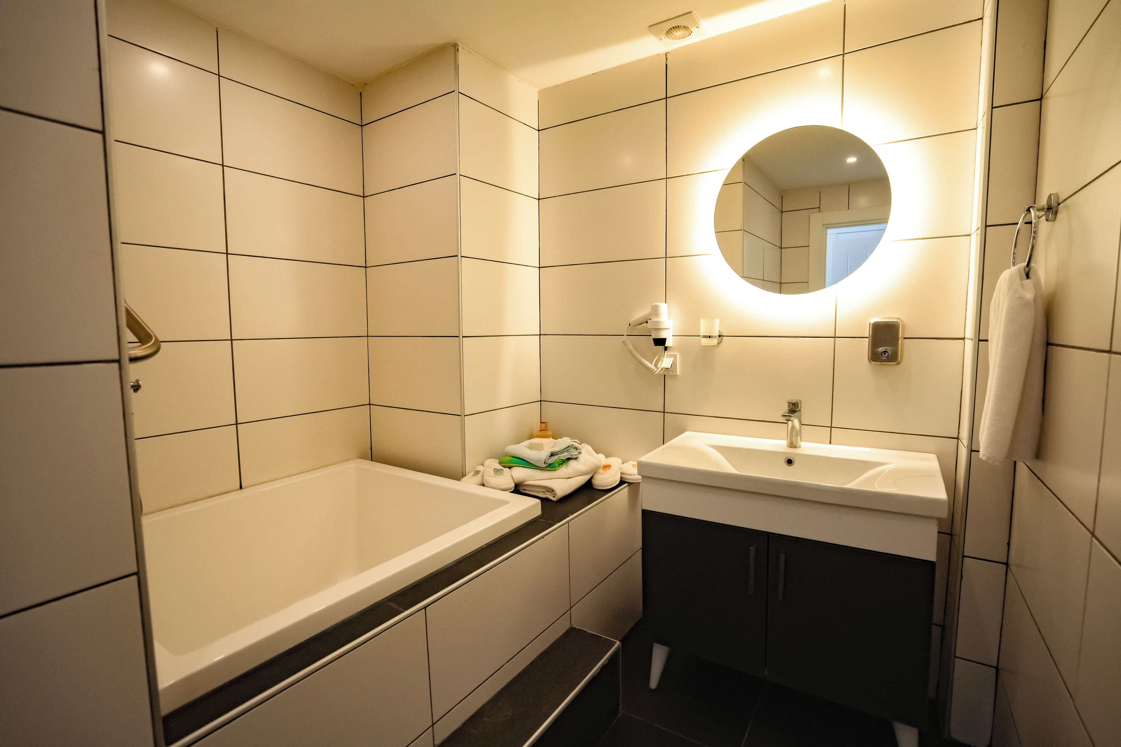 A modern bathroom with a bathtub, a sink, and a mirror.