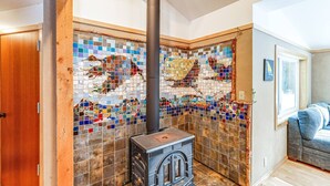 A room with a mosaic wall, a wood-burning stove, and a door.