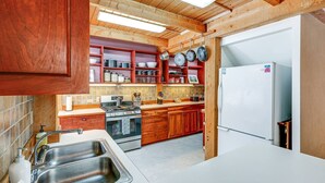 A kitchen with wooden cabinets, a stove, a sink, and a refrigerator.