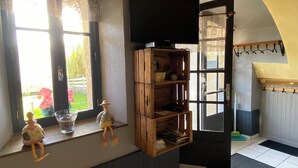 A room with a large window, a wooden shelf, and a door leading to another room. - Champsaur : Authentic gîte 1250m - Exceptional mountain view - Garden (Saint-Bonnet-en-Champsaur)