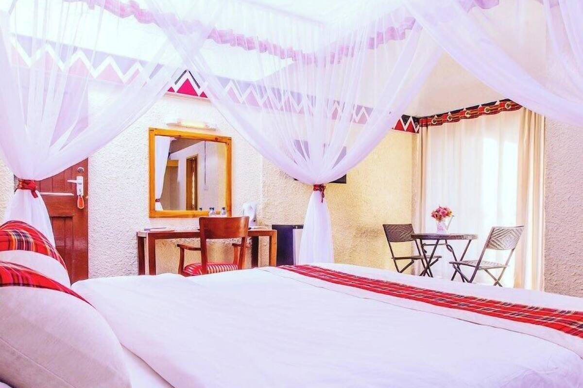 A hotel room with a bed, a desk, a chair, and a table.