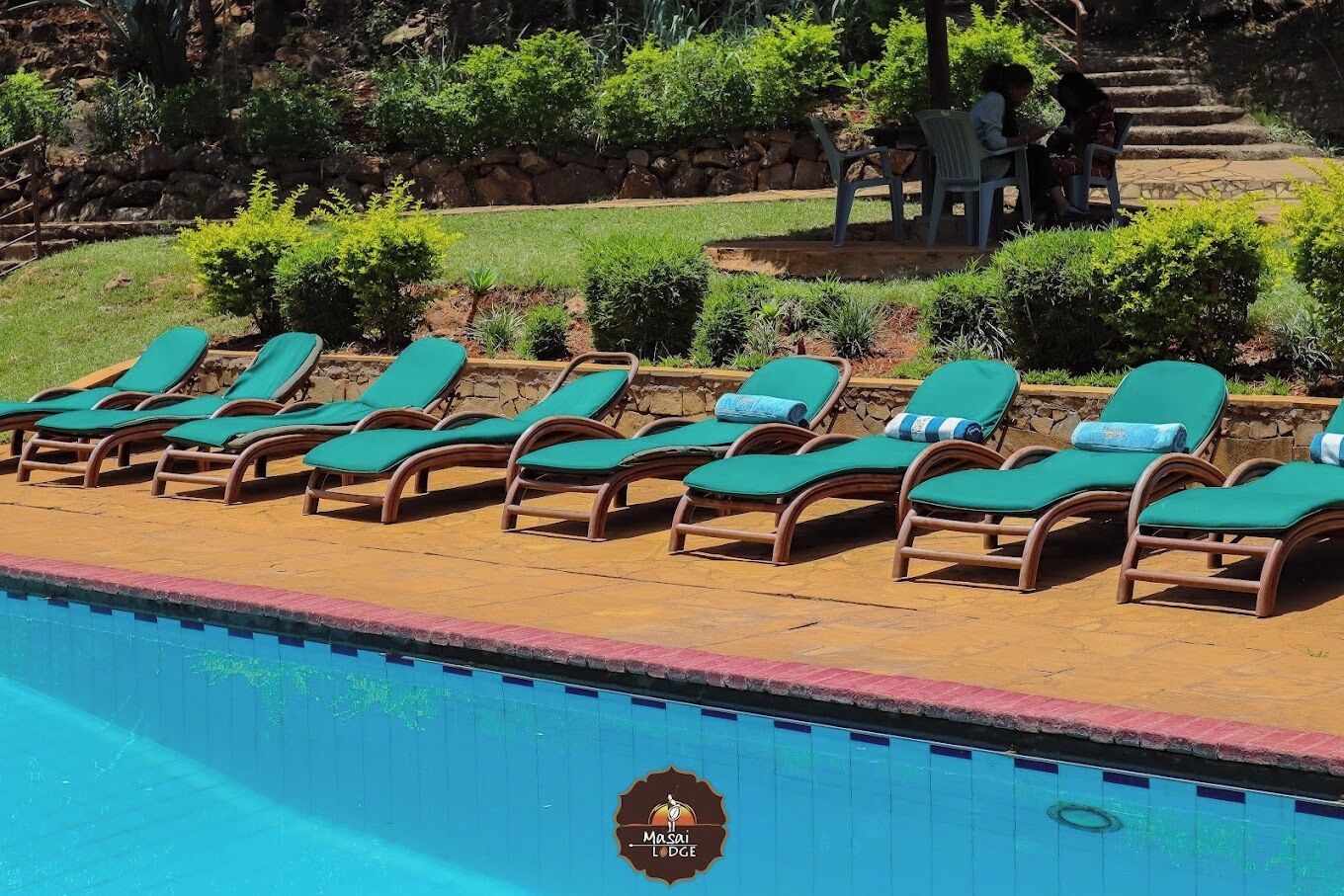 Area piscina con lettini e parete in pietra.