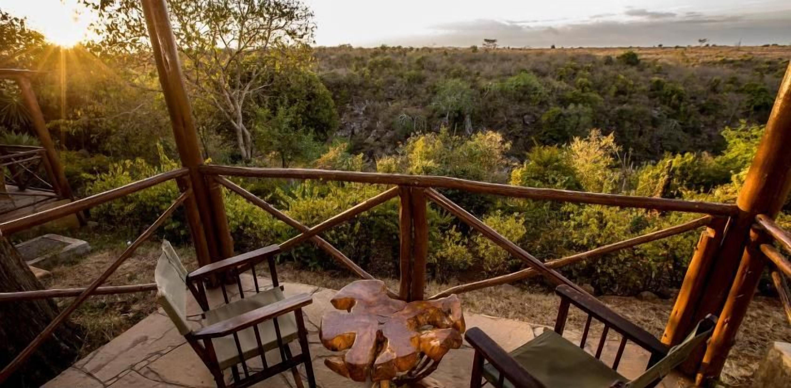 A wooden deck with a table and chairs overlooking a natural landscape.