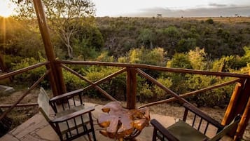 A wooden deck with a table and chairs overlooking a natural landscape.