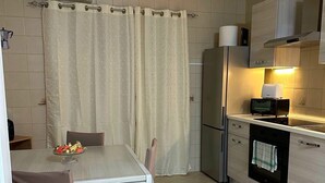 A compact kitchen with a dining area, including a table with chairs, a refrigerator, a microwave, and a stove.