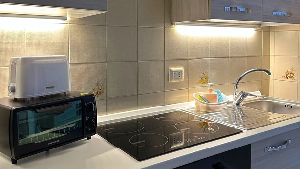 A modern kitchen with a built-in toaster, a black induction cooktop, a stainless steel sink, and a dishwasher.