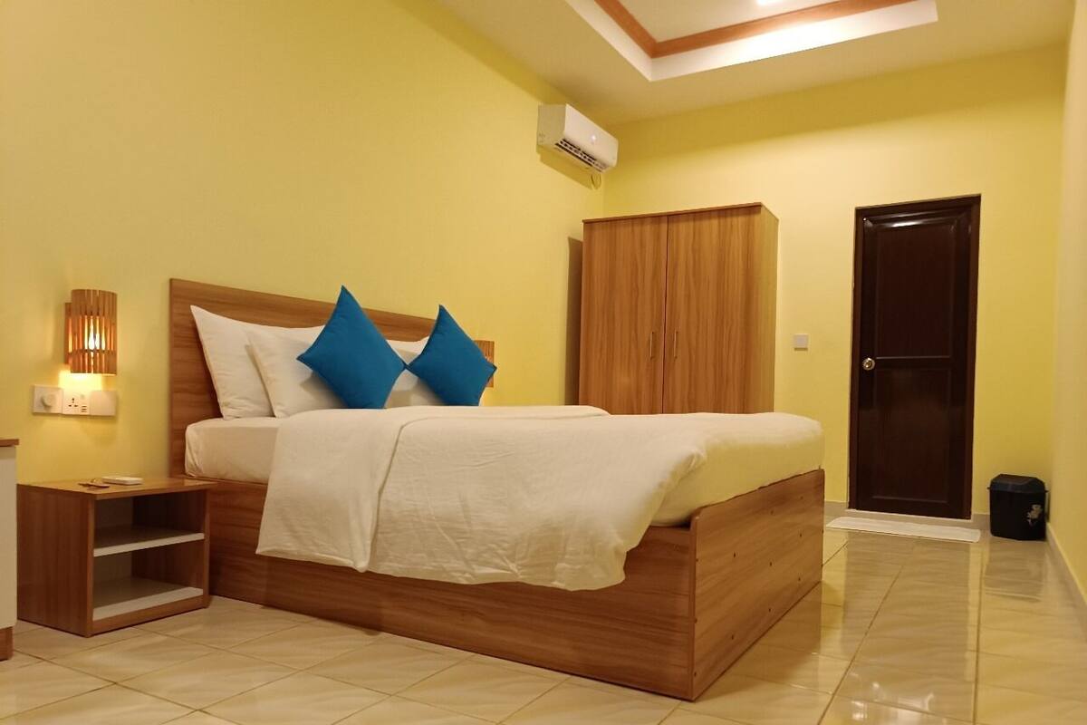 A bedroom with a wooden bed, a nightstand, a wardrobe, and a door.