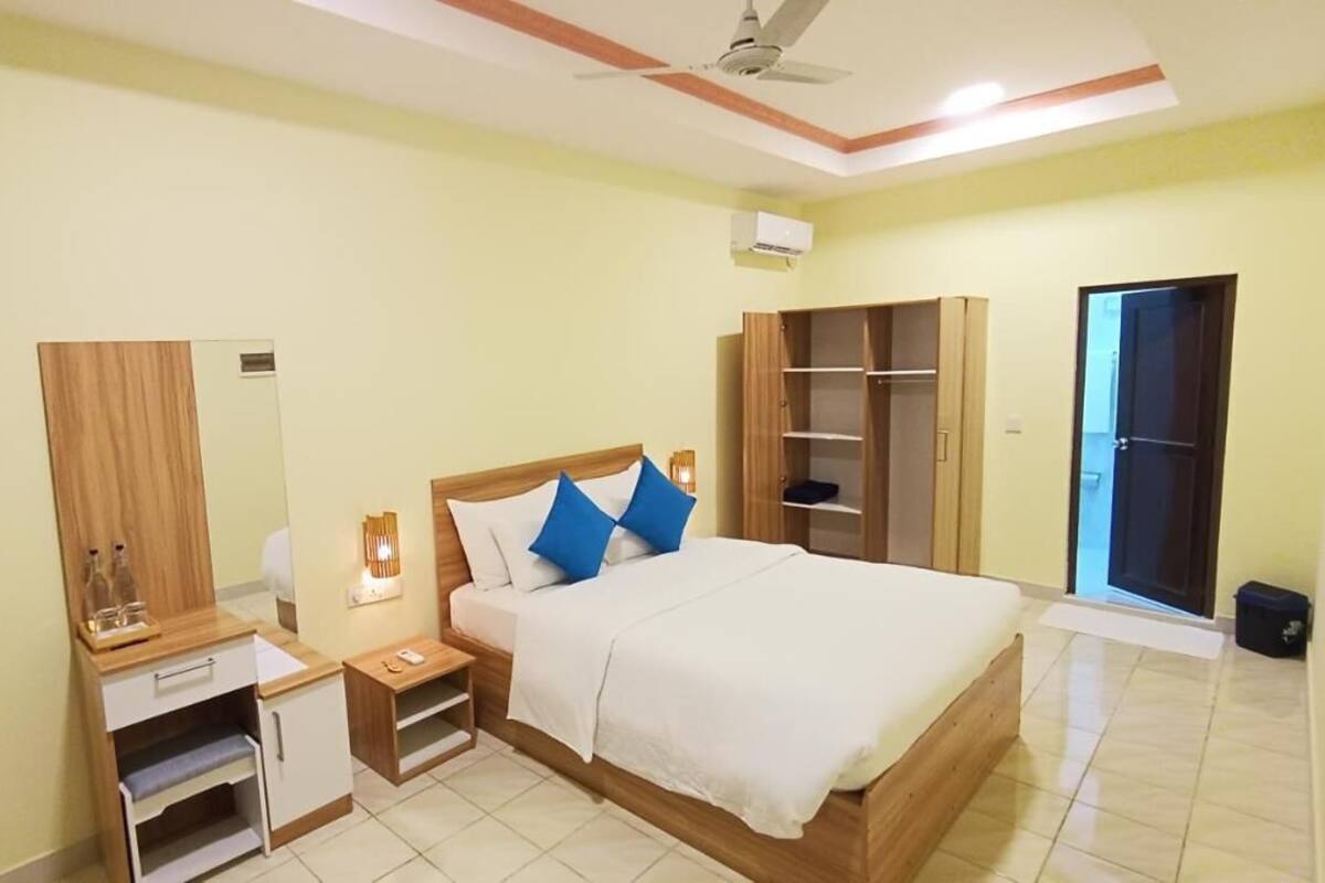 A bedroom with a bed, bedside tables, a wardrobe, and a mirror.