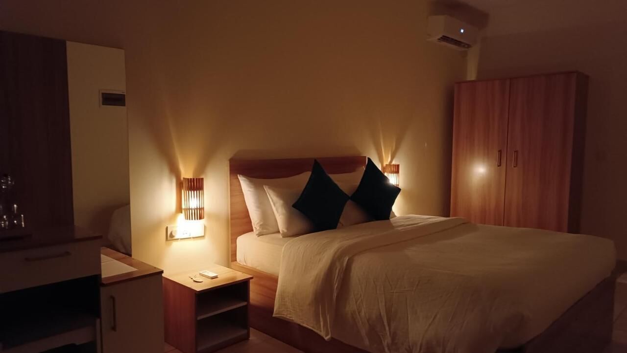 Une chambre d’hôtel bien rangée, avec un lit, une table de chevet, une lampe, une armoire et un miroir.