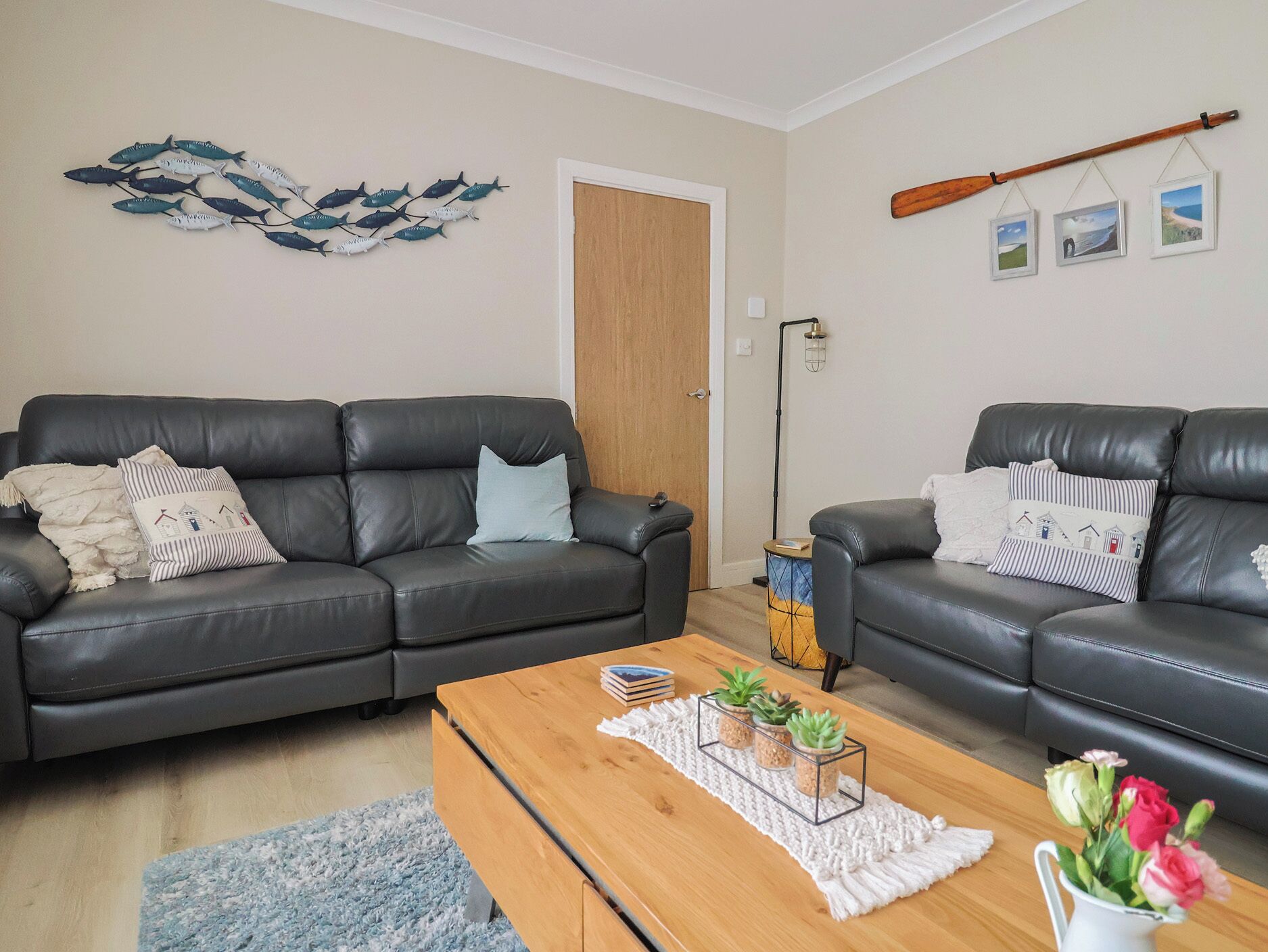 A living room with two black leather sofas, a wooden coffee table, and a blue shaggy rug.