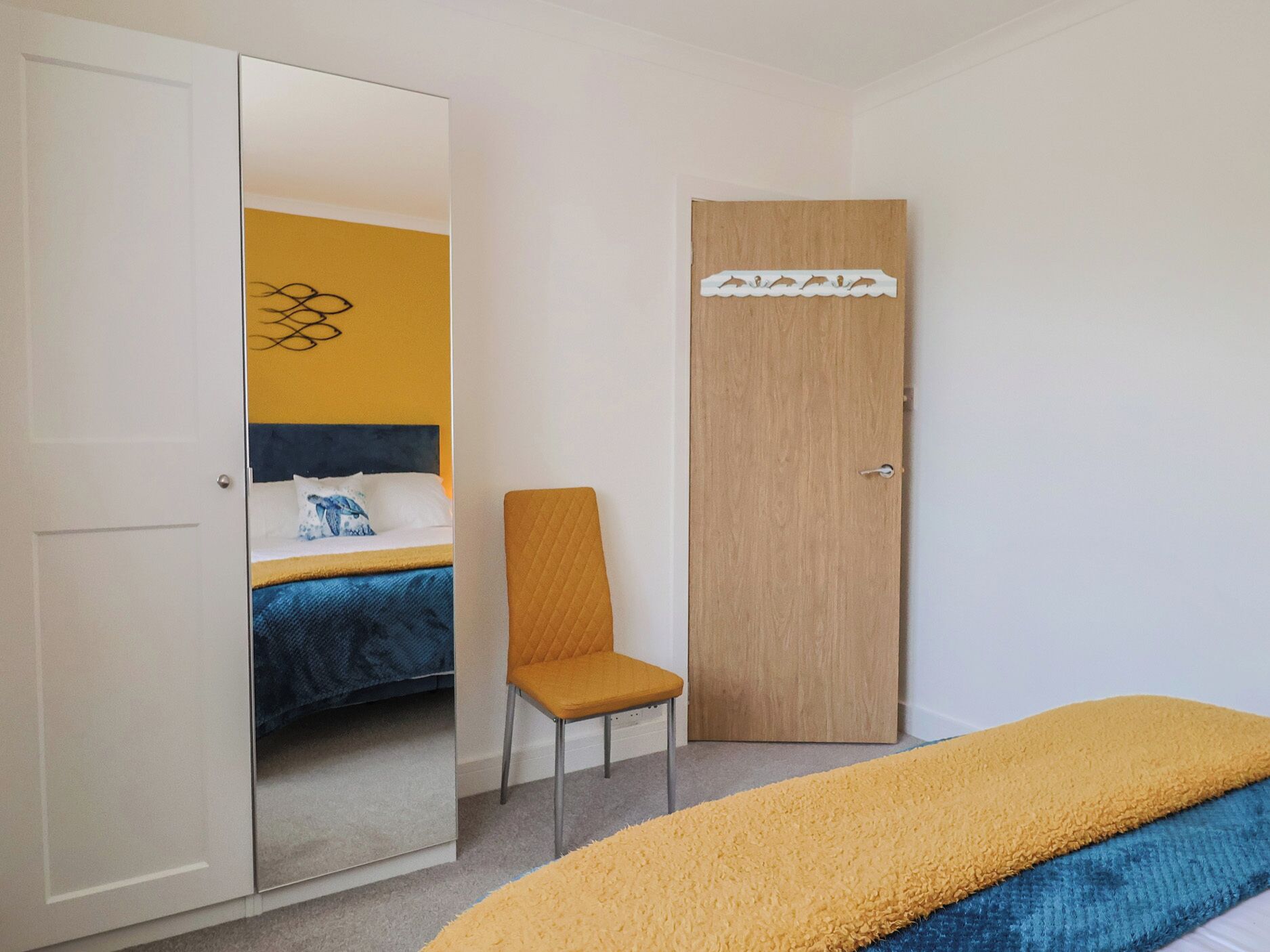 Een slaapkamer met een bed, een stoel, een kledingkast en een spiegel.