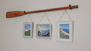 Tre inramade bilder hänger på en vägg, och ovanför dem finns en träpaddel.