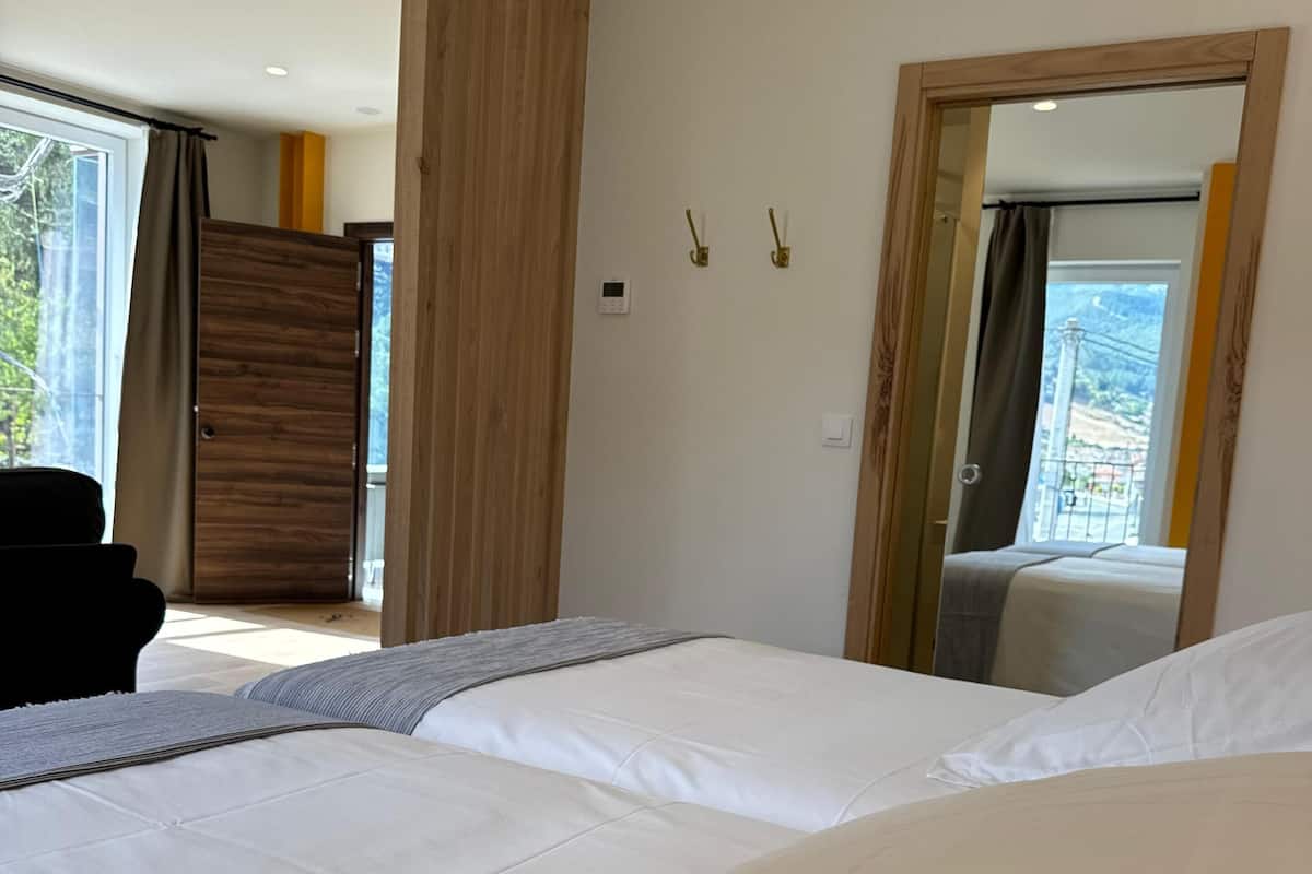 A modern hotel room with a large bed, a wooden wardrobe, and a view of the outdoors through a window.