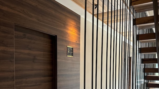 A modern interior with a wooden door, a metal railing, and a sign indicating room number 213. - ARENAS SUITES APARTAMENTOS (Potes)