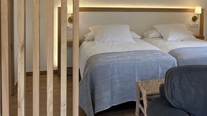 A hotel room with two beds, a wooden floor, and a grey sofa. - ARENAS SUITES APARTAMENTOS (Potes)