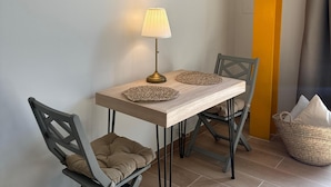A dining area with a table, chairs, a lamp, and a woven basket. - ARENAS SUITES APARTAMENTOS (Potes)