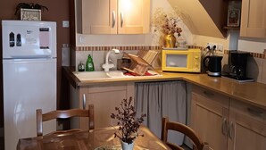 Une cuisine compacte avec un coin repas, comprenant un réfrigérateur, un four à micro-ondes, un évier et des placards en bois.
