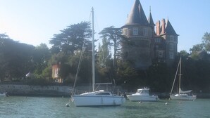 Un bâtiment historique doté d’une tour et de plusieurs flèches, entouré d’eau et de bateaux.