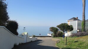 Une route côtière menant à un bâtiment d’où l’on a vue sur la mer.