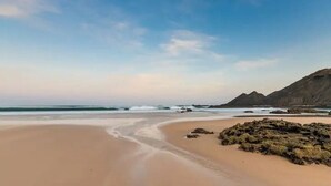A beach with a clear sky, sandy shore, and rocky outcrops. - Ocean Whisper-spectacular villa on Portugal's west coast (Aljezur)