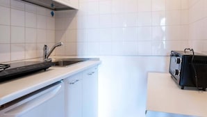 Una cocina con armarios blancos, un lavamanos de acero inoxidable, un tostador negro y un horno empotrado.