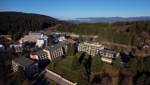 An aerial view of a residential area with multiple apartment buildings, surrounded by dense forests and hills in the background. - Apartment Luna, Sankt Englmar (Sankt Englmar)
