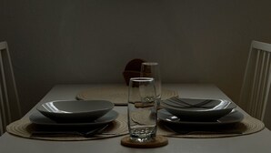 A dining table with plates, cutlery, and a glass set against a wall with a large illuminated moon artwork. - Apartment Luna, Sankt Englmar (Sankt Englmar)