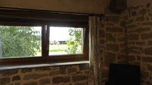 A room with a stone wall and a window overlooking a garden. - Spacious cozy and pet friendly Gîte (6pers with 3 bdrms/2 baths/3 toilets). (Claudon)