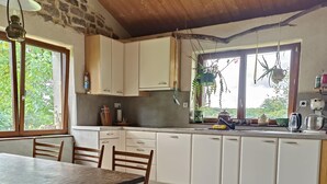 A kitchen with white cabinets, a wooden table, and patterned floor tiles. - Spacious cozy and pet friendly Gîte (6pers with 3 bdrms/2 baths/3 toilets). (Claudon)